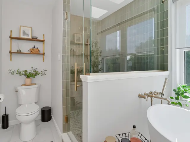 White toilet beneath open shelving beside the green-tiled glass shower and freestanding tub.