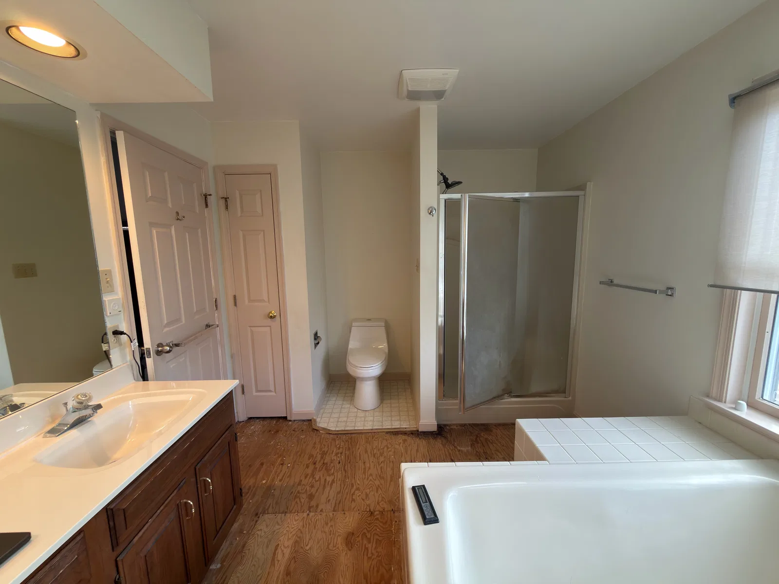 Before remodeling: framed shower, toilet alcove and wood vanity beside the built-in bathtub.