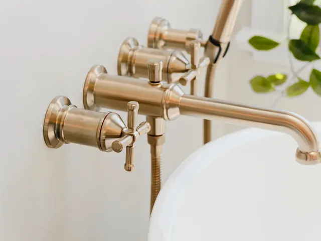Close-up of gold-tone cross-handle controls and a curved bathtub spout.