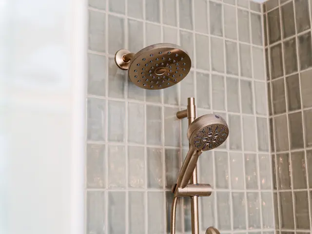 Close-up of the round showerhead and handheld spray against green shower tile.