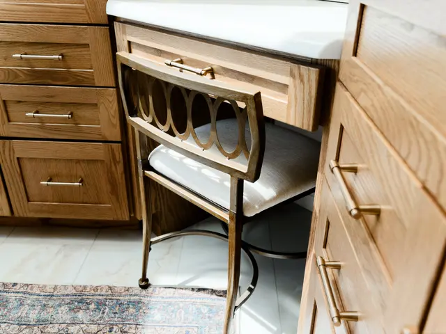 Bathroom makeup desk and upholstered chair between matching wood vanity cabinets.