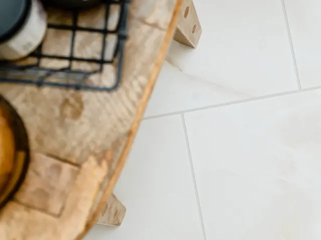 Bathroom tray with small containers beside pale herringbone floor tiles.