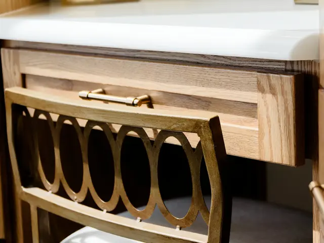 Wood makeup-desk drawer above a chair with an oval-patterned metal back.