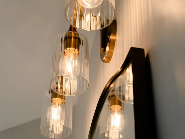 Close-up of glowing glass vanity-light shades beside the mirror frame.