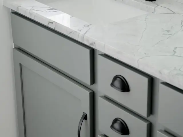 Gray vanity with black hardware and a marble-look countertop beneath a black-framed mirror.