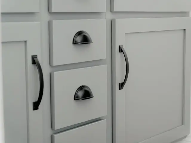 Close-up of gray vanity doors and drawers with dark cup pulls and curved handles.