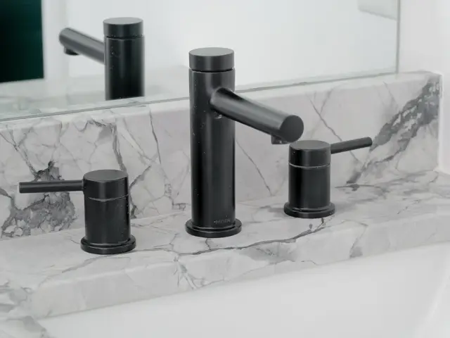 Black faucet and handles above the white vanity sink and veined countertop.