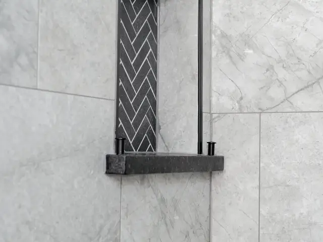 Recessed shower niche with dark herringbone tile and a narrow shelf.