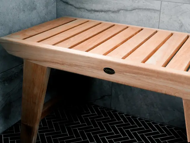 Closer view of the slatted wood shower bench against gray tile.