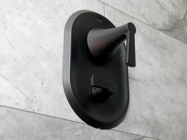 Matte-black shower control set into a gray tiled wall.
