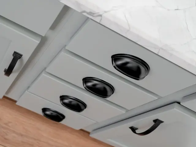 Gray vanity drawers with dark cup pulls beneath a veined countertop.