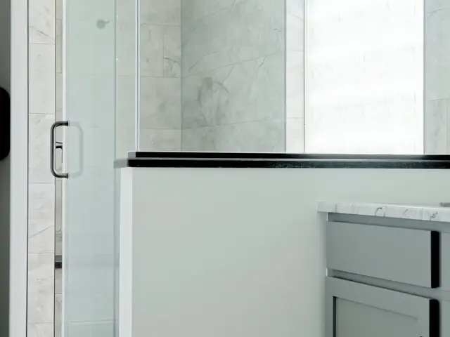 Vertical view along the shower glass toward the tiled wall and frosted glass-block window.