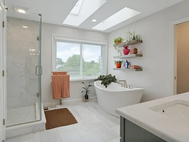 Finished bathroom overview with a glass shower, freestanding tub beneath floating shelves, a window and two skylights.