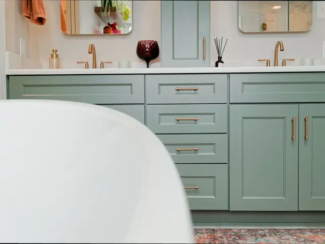 Blue-green vanity drawers and cabinet doors behind the curved white bathtub.