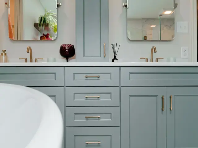 Double vanity with a tall central storage cabinet, pale countertops and gold-tone faucets.
