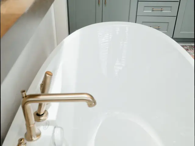 View along the bathtub rim toward the blue-green vanity and its drawers.