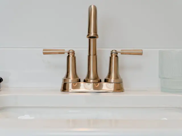 Close-up of a gold-tone widespread vanity faucet and handles above the sink.
