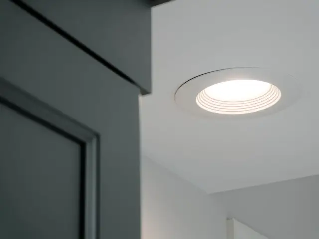 Close-up of a recessed ceiling light beside the tall blue-green vanity cabinet.