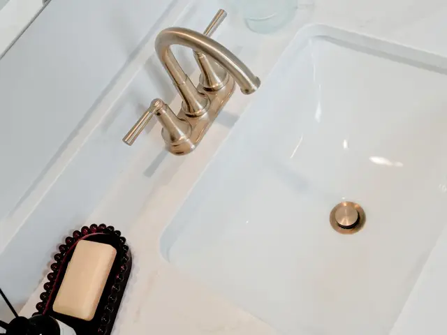 Overhead view of a white vanity sink with gold-tone faucet and a hairbrush.