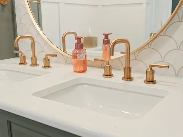 Undermount white sink with a brushed-gold faucet below a scalloped tile backsplash.