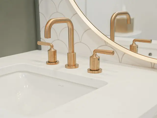 Angled view of a brushed-gold vanity faucet beside the sink and scalloped backsplash tile.
