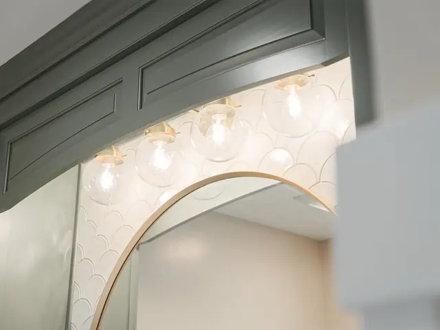 Dark green vanity alcove with a gold-framed arched mirror and warm lighting.