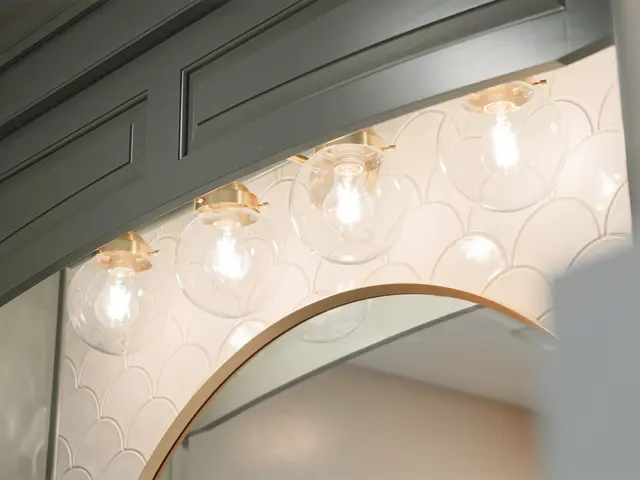 Arched gold mirror and warm vanity lights above the sage green cabinet.