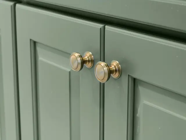 Close-up of sage green cabinet doors with gold-tone round knobs.