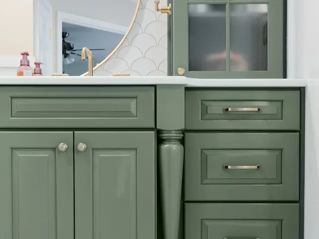 Vertical view of the sage green vanity cabinet with a gold-framed mirror and tall storage tower.