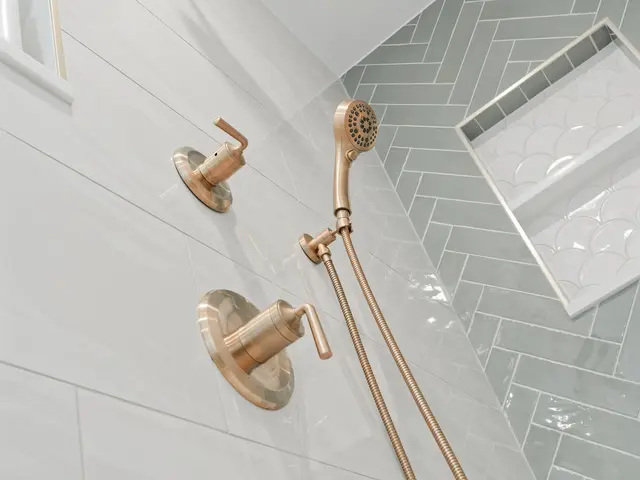 Vertical view of the brushed-gold shower fixtures and a recessed niche in green herringbone tile.