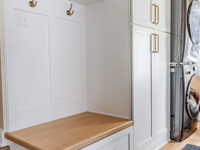 Finished Hummelstown project with a wood-topped built-in bench, white storage cabinetry, warm metal hooks and handles, and an adjacent stacked washer and dryer.