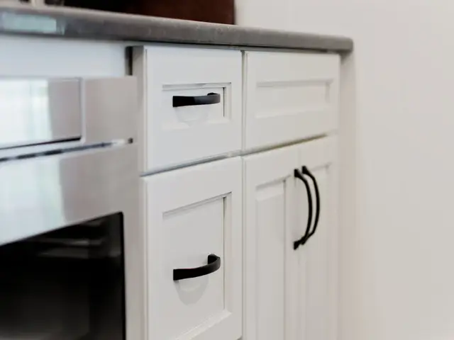 Built-in stainless beverage refrigerator beside white drawers and base cabinetry.