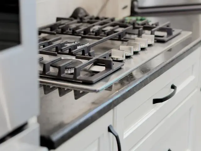Close-up of the gas cooktop burners and control knobs above white kitchen drawers.