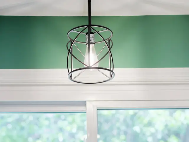 Open-frame pendant light above the kitchen window against a green accent wall.