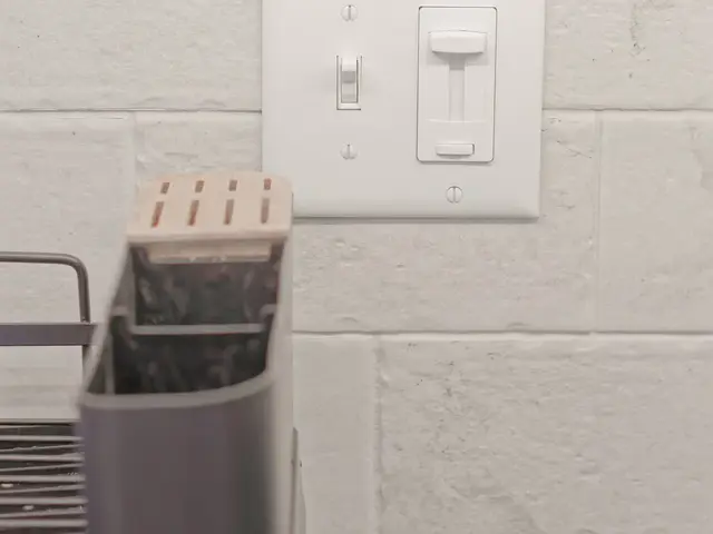 Light brick-pattern kitchen backsplash with a white switch plate beside the sink accessories.