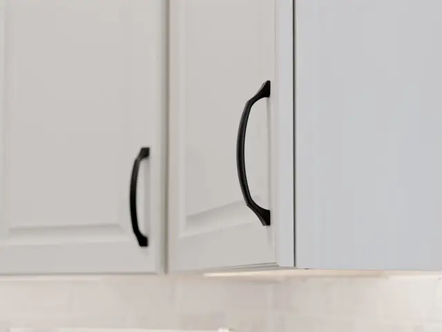 White upper cabinet doors with curved black pulls above the light kitchen backsplash.