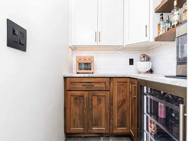 Wood corner cabinetry beneath a light countertop beside a built-in beverage refrigerator.
