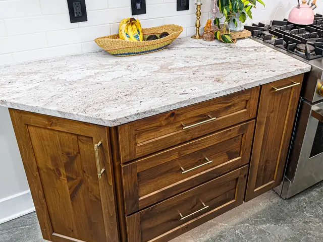 Close-up of a light veined countertop above wood drawers beside the gas range.
