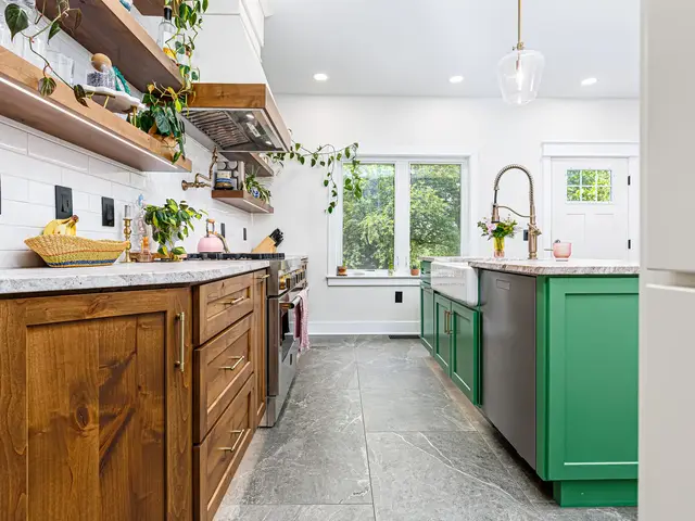 Low view along wood kitchen cabinets toward the green island and window wall.